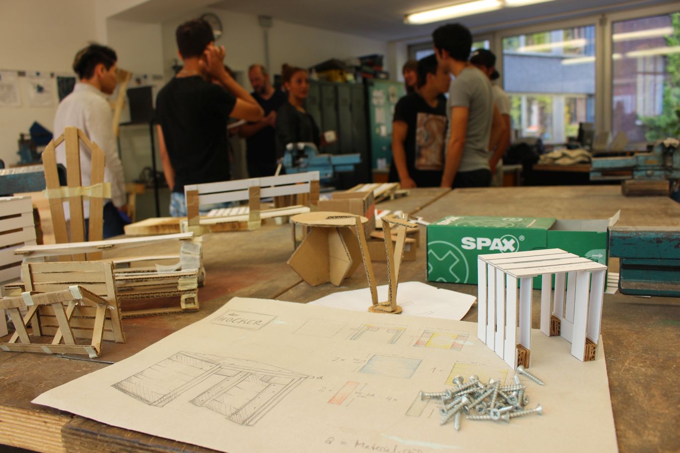 Das Foto zeigt einen Bauplan und Modelle aus Pappe