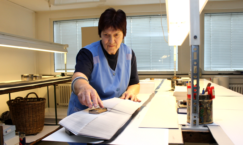 Das Foto zeigt eine Frau bei der Arbeit an einem Papierstapel