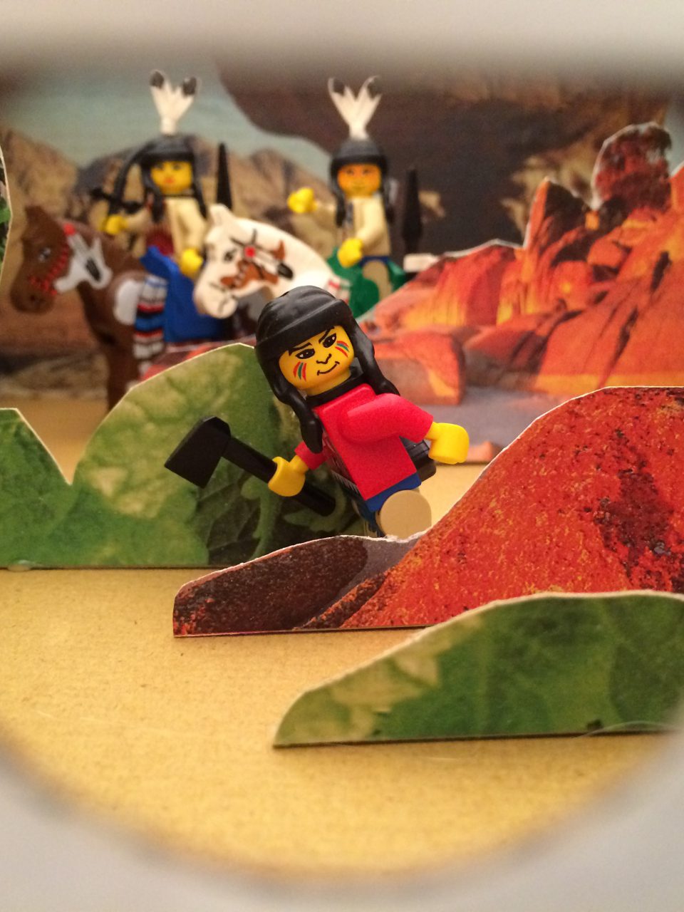 Das Foto zeigt Playmobil Indianer in einer Landschaft aus Papierhügeln
