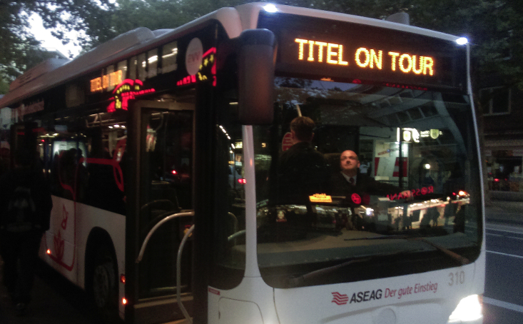 Das Foto zeigt einen Bus mit der Aufschrift Titel on Tour