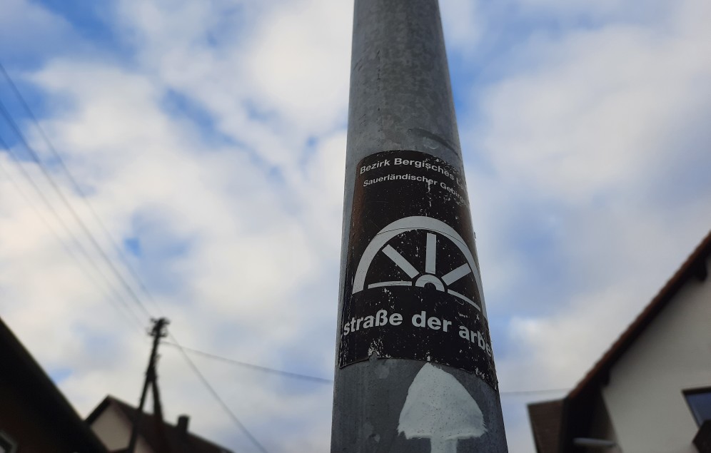 Sticker "Die Straße der Arbeit" an Laternenpfahl
